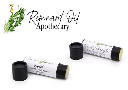 Two Remnant Oil Apothecary 'Quiet Strength' and 'Abide' lip balm tubes with black caps removed, displayed on a white background with brand text and rosemary illustration.