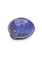 A small organic-shaped ceramic teaspoon dish or jewelry holder in a deep matte blue glaze with lighter speckled highlights, shown on a plain white background.