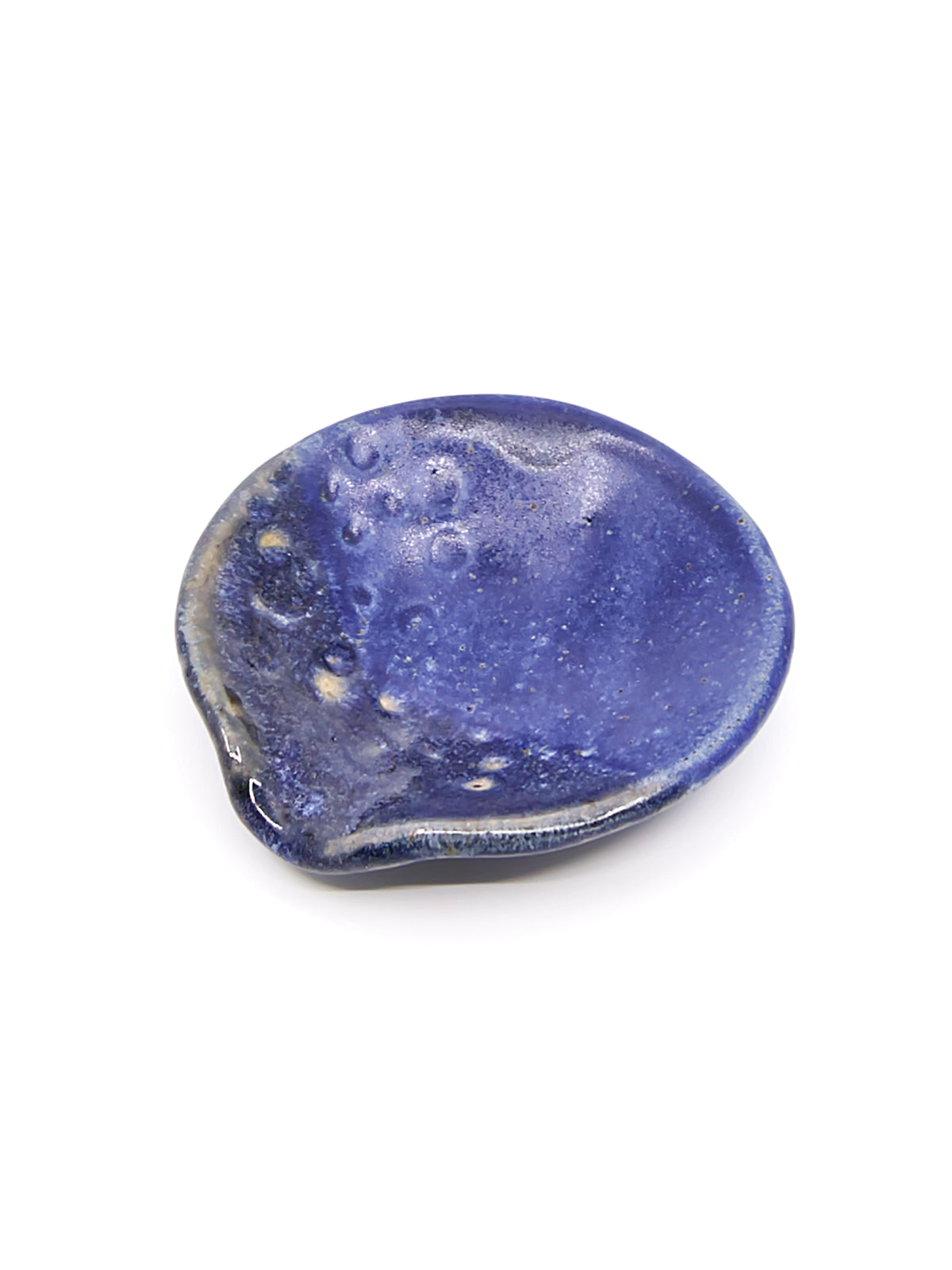 A small organic-shaped ceramic teaspoon dish or jewelry holder in a deep matte blue glaze with lighter speckled highlights, shown on a plain white background.