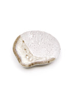 A small organic-shaped ceramic teaspoon dish with a glossy white glazed top and a speckled, matte beige-brown rim, photographed on a clean white background.