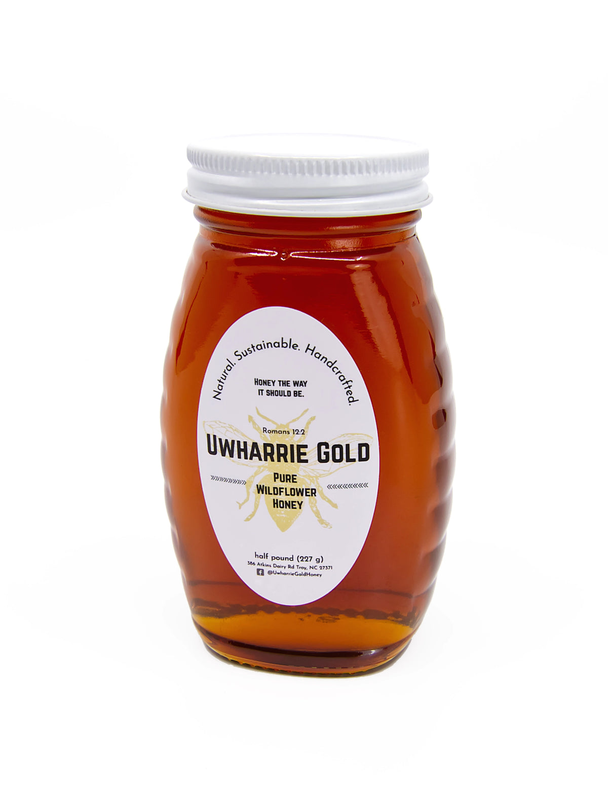 A glass jar of Uwharrie Gold Pure Wildflower Honey with a white screw cap and a white oval label, shown on a plain white background.