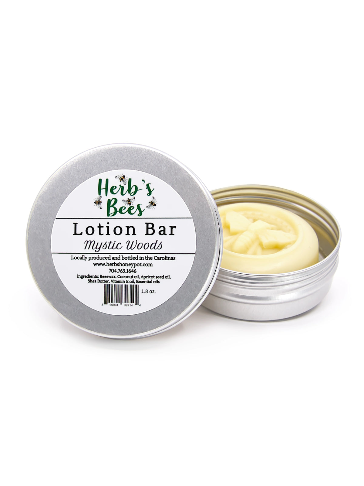 An open silver metal tin of Herb's Bees Lotion Bar in the 'Mystic Woods' scent, showing the pale yellow lotion inside, next to its lid which features a white label.